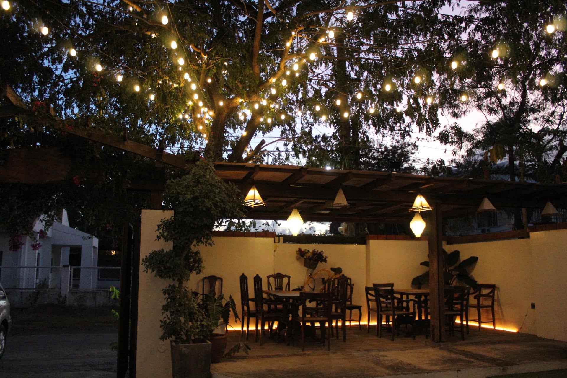 The garden pergola at dusk beneath a canopy of string lights