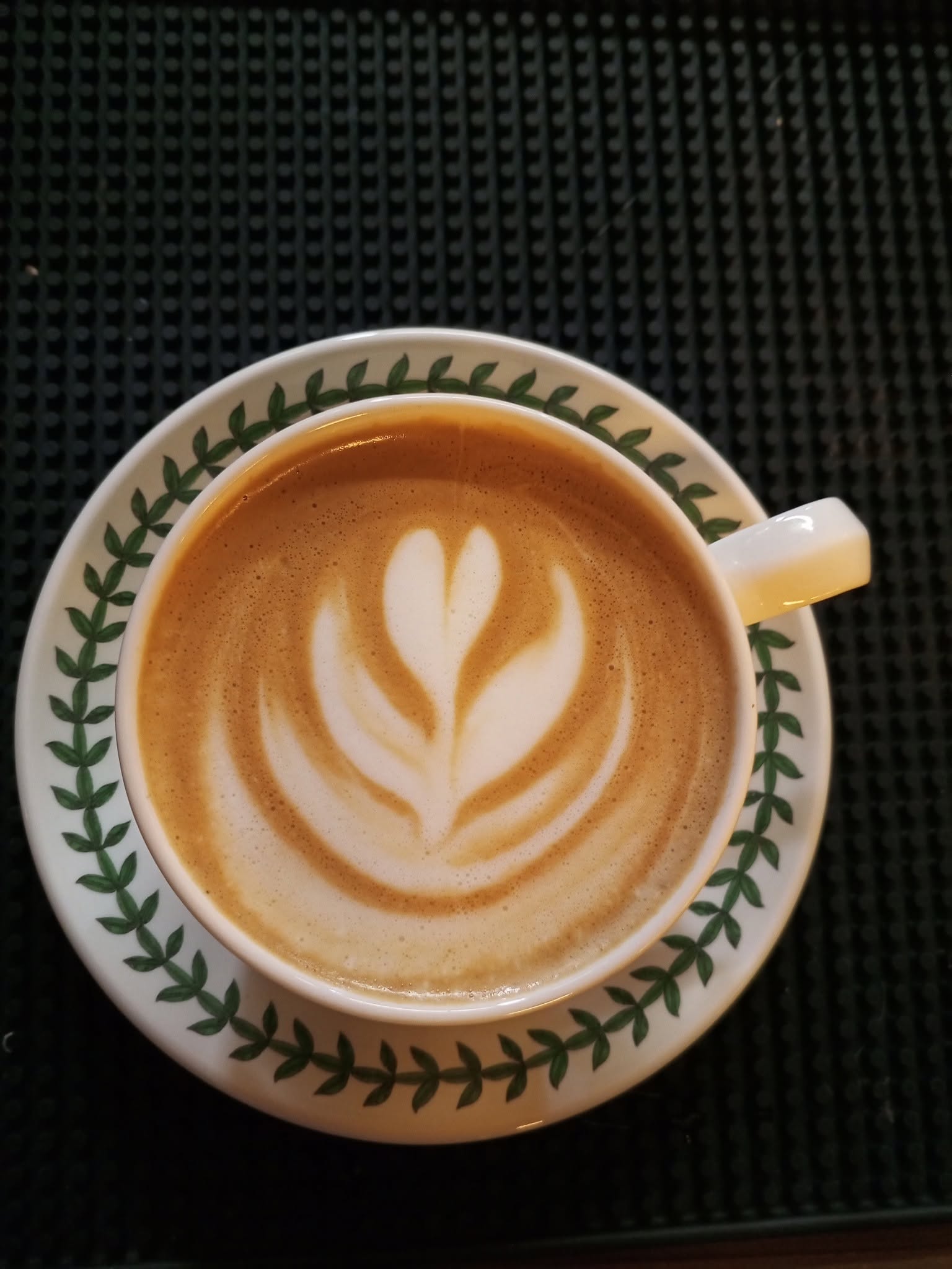 Creamy cappuccino with tulip latte art in a leaf-patterned cup